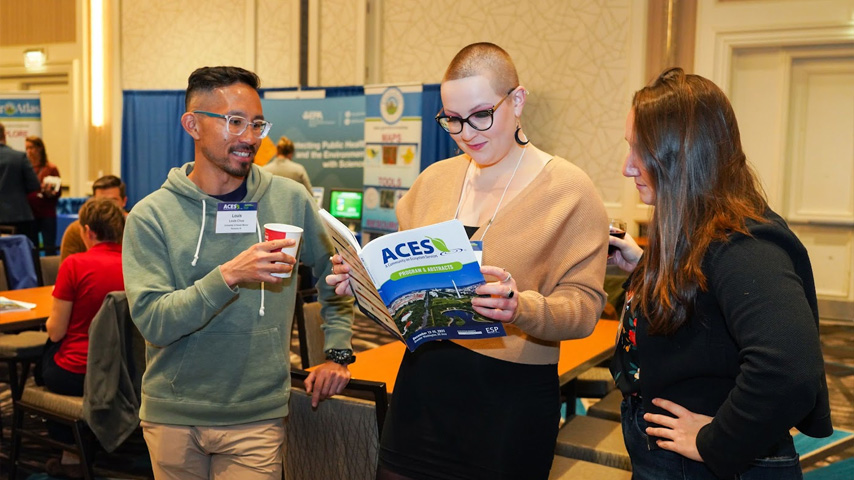 ACES attendees conversate while holding a program book