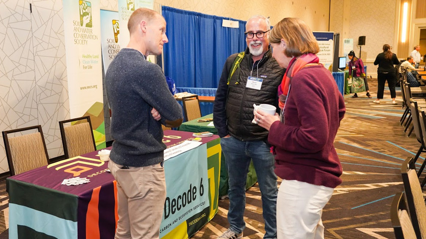 ACES attendees laugh and conversate around an exhibit booth